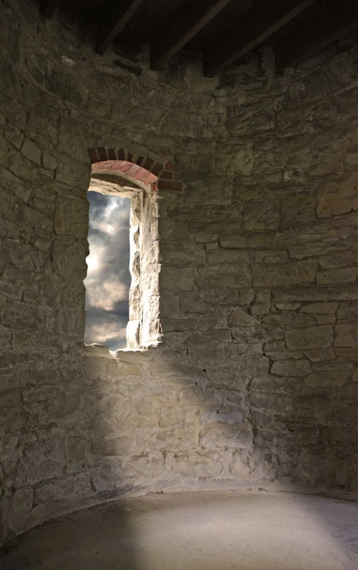 a stone wall with an open window with cloudy sky and light coming through the windows