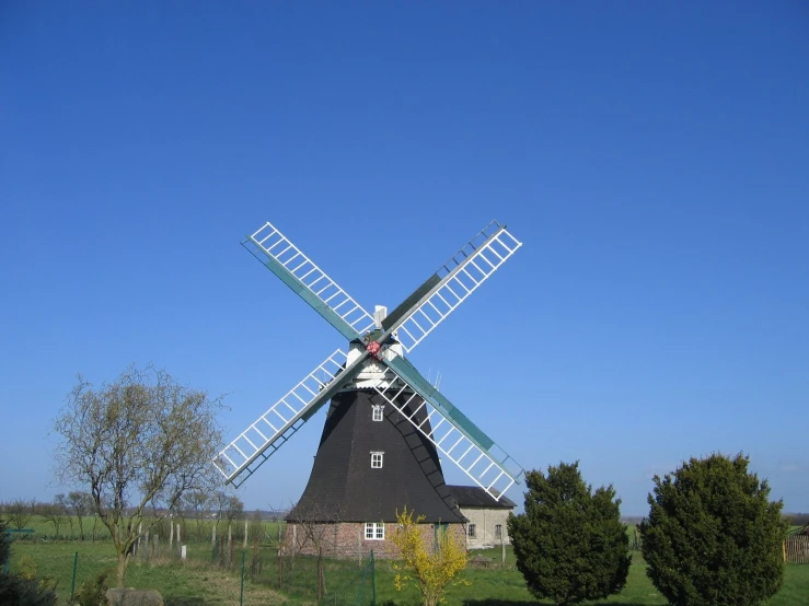 a black windmill with trees around it