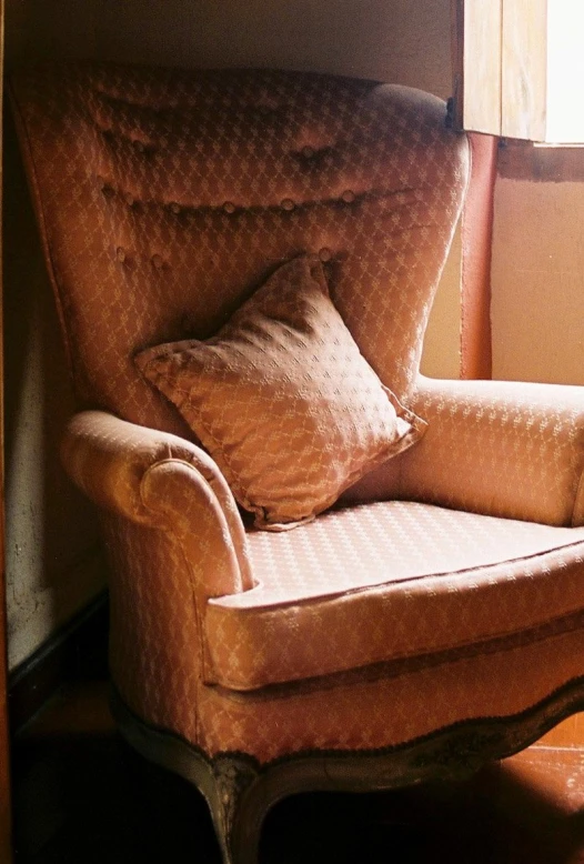 a chair with some pillows on it near a window
