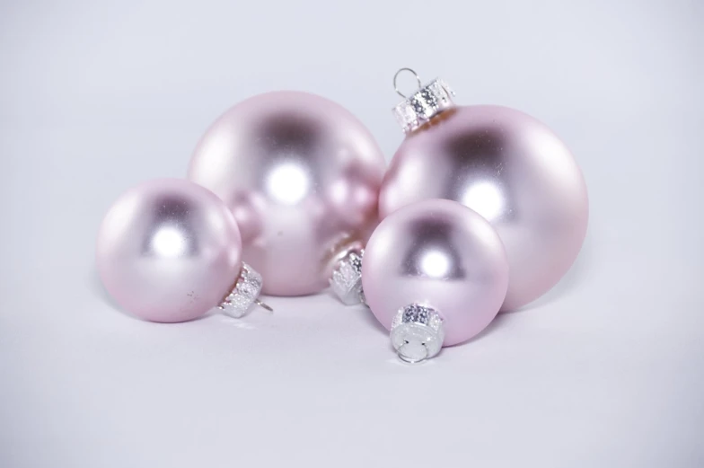 a group of shiny pink ornaments on a white background