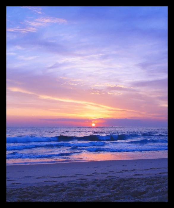 a sunset on the beach with waves coming in