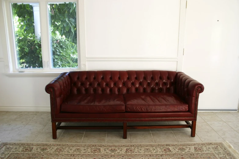 a red leather couch in front of two windows