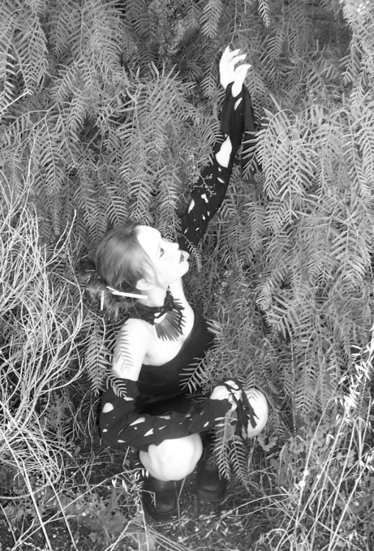 a woman sitting on the ground and touching her hand near some trees