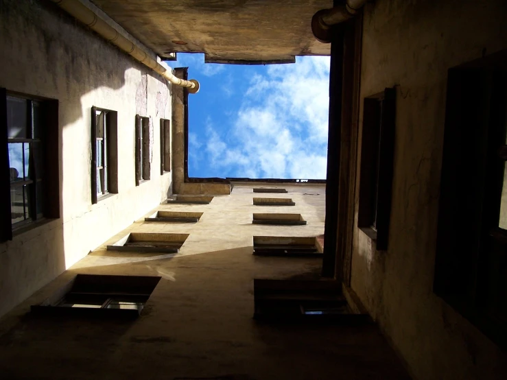 an alley way with multiple windows and several wooden benches