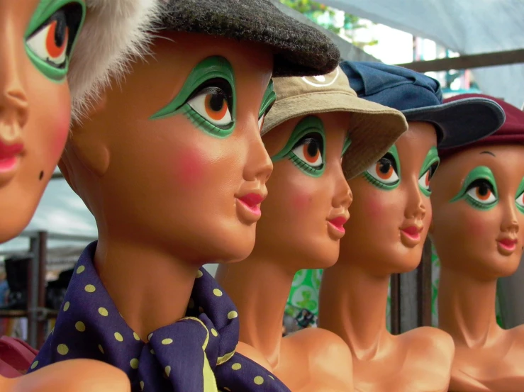 a number of dummy heads are dressed in green makeup