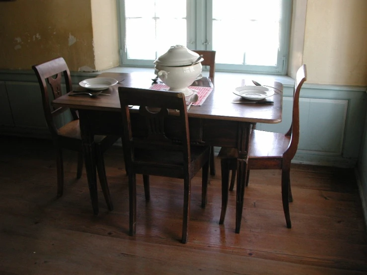 a set of chairs sitting around a table with tea pot