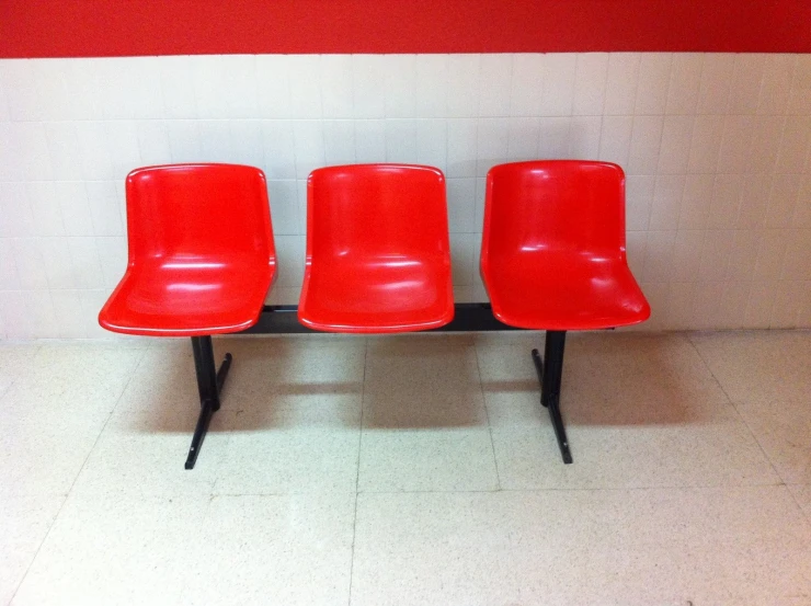 three red chairs in a white tiled hallway