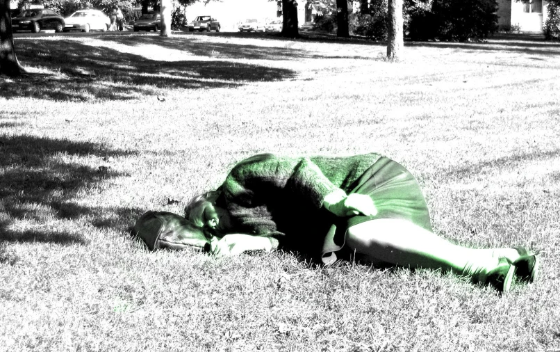 a person lays on the ground on their side in a park