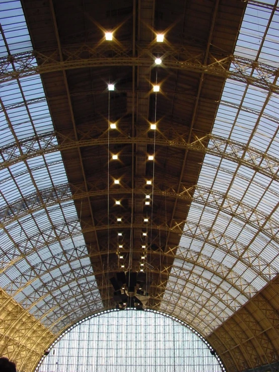 several people walk underneath the large ceiling in a subway station