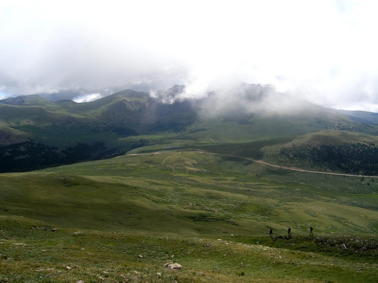 the green hills are covered with fog and cloud