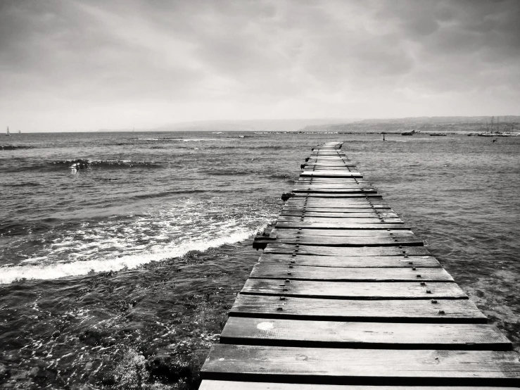 black and white po of wooden boardwalk leading to ocean