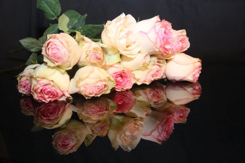 a pile of pink and white roses on top of a black background