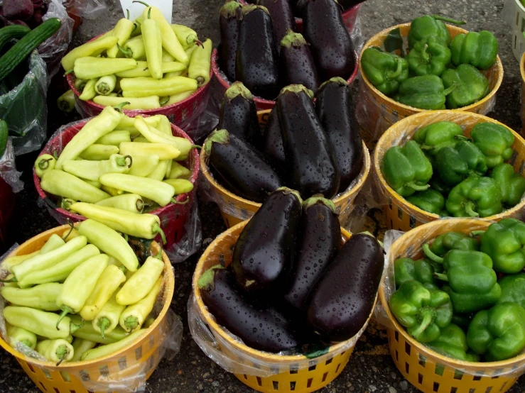 several baskets with eggplants and peppers on them