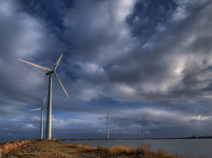 the three windmills are near a body of water