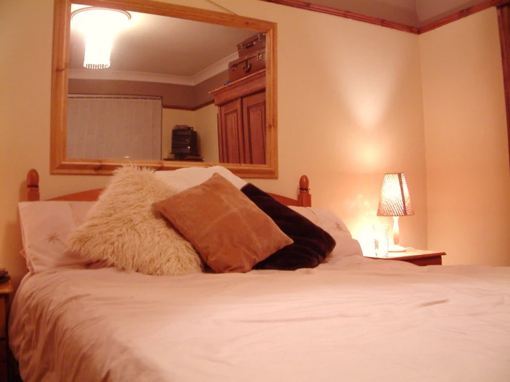 the large bed has white sheets and a gold throw pillow