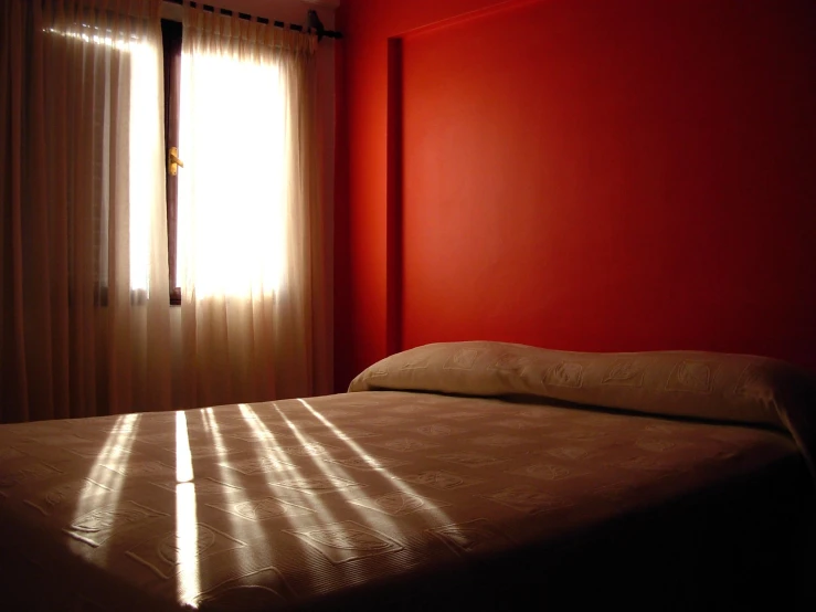 a bed in a room next to a window with sun streaming through it