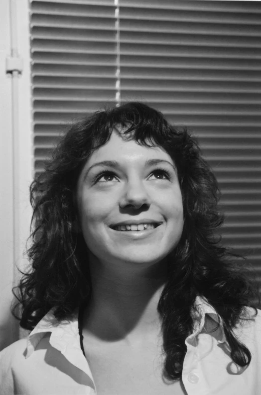 a smiling woman with long hair, wearing shirt and looking into camera