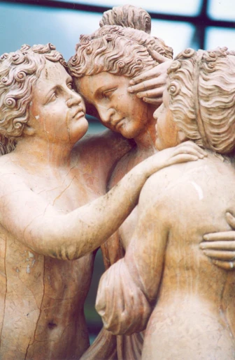 three statues of different sizes hugging each other
