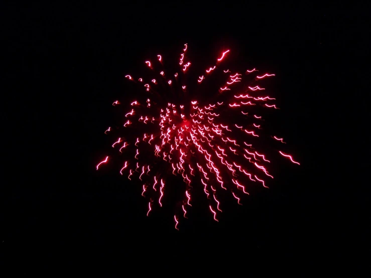 a big red firework with a dark sky background