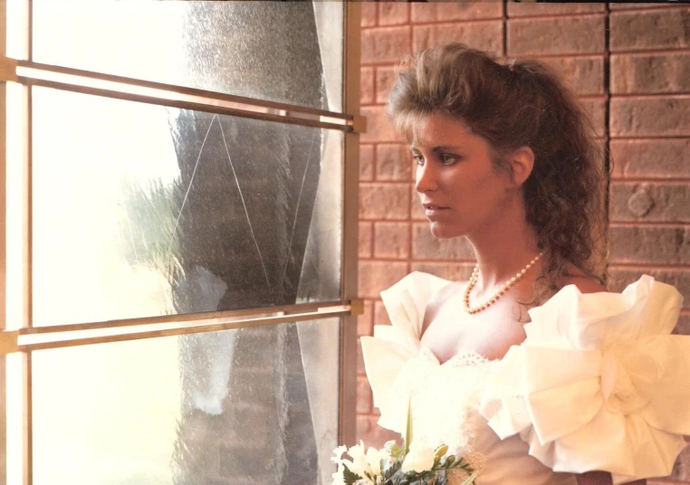 an elegant bride leans against the windowsill