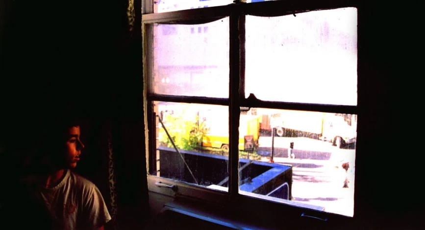 man standing in front of window with buildings outside