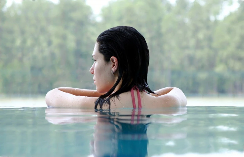 a woman is sitting in the water and looks away