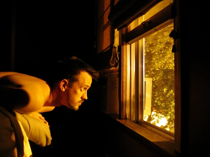 man looking out of window at trees outside