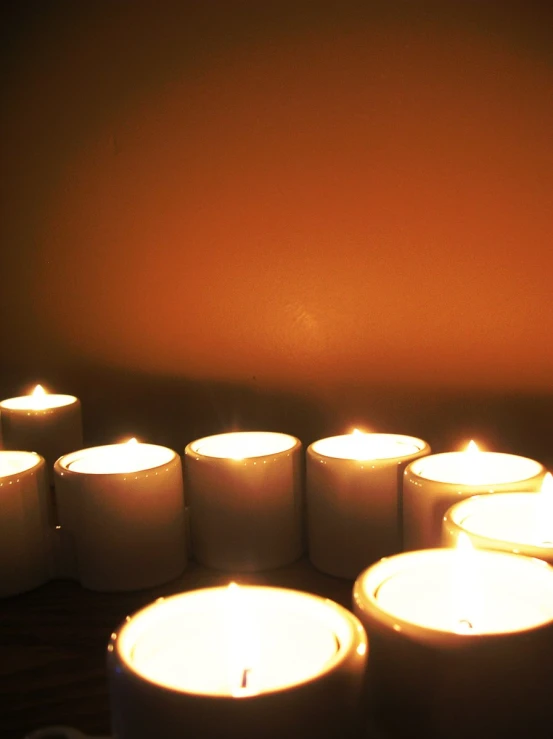 many lit candles in a circle with a brown wall