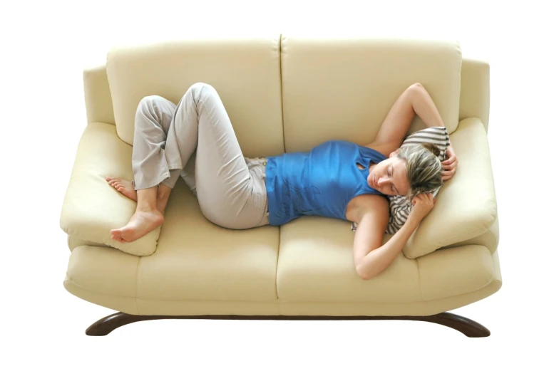 a woman laying on top of a tan leather couch