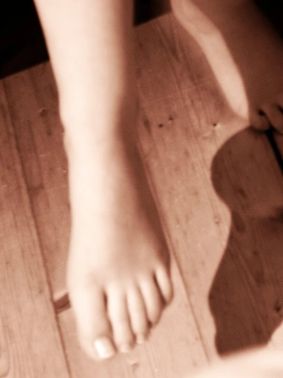 a persons bare feet on a wooden floor