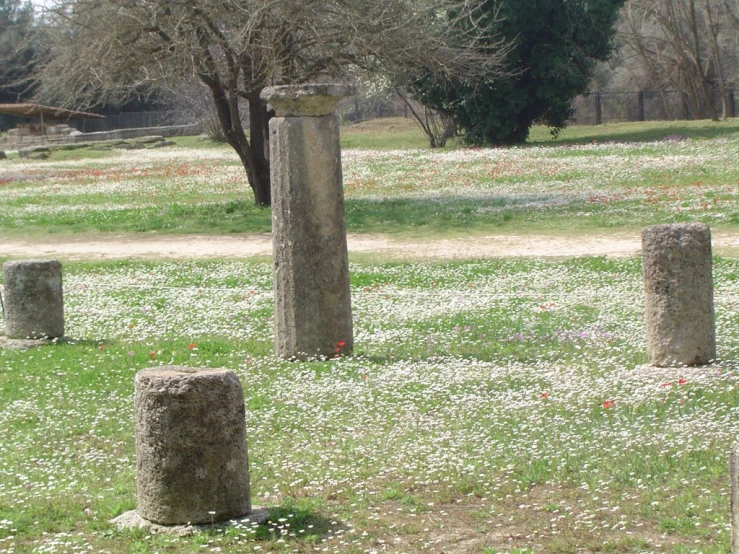 a field with three stone stands and flowers in it