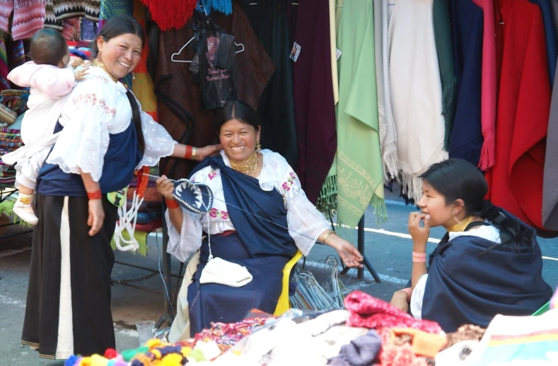 a woman holding a small baby near an outside market