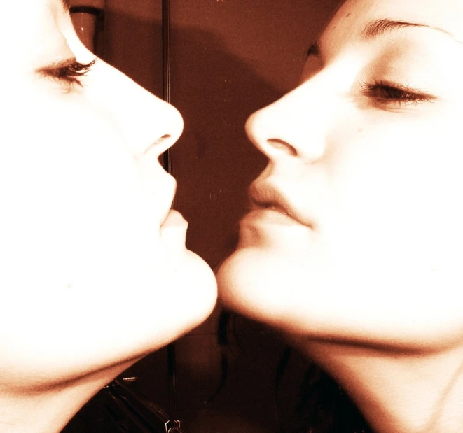 a close up image of two beautiful women looking in the mirror