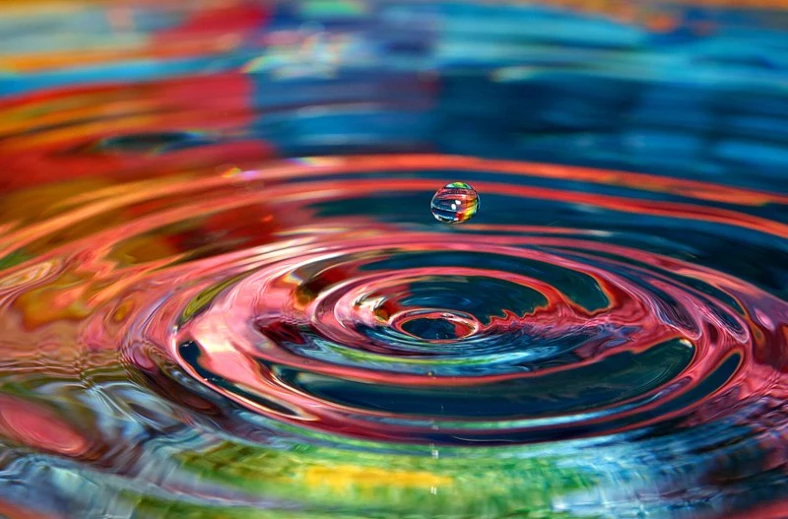 water droplets in rainbow colored water ripples