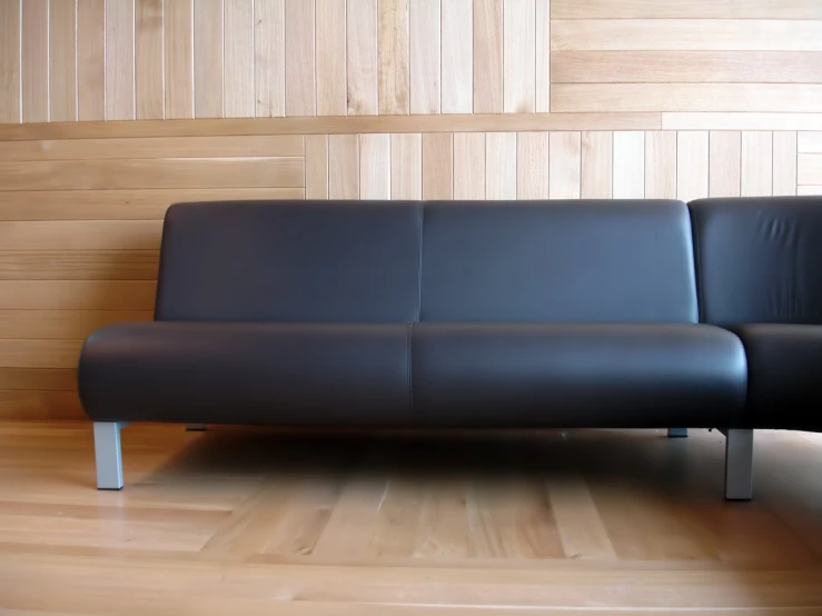 a couch sitting on top of a wooden floor next to a wall