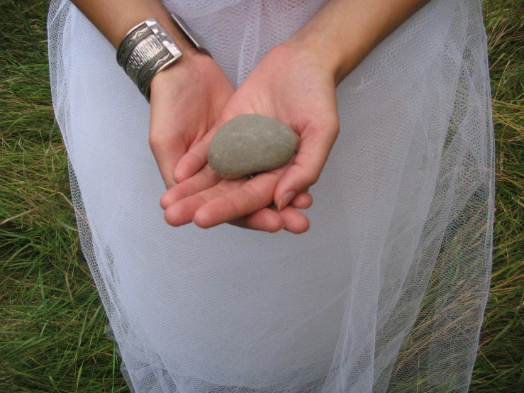 a woman holding a stone and showing it to the camera