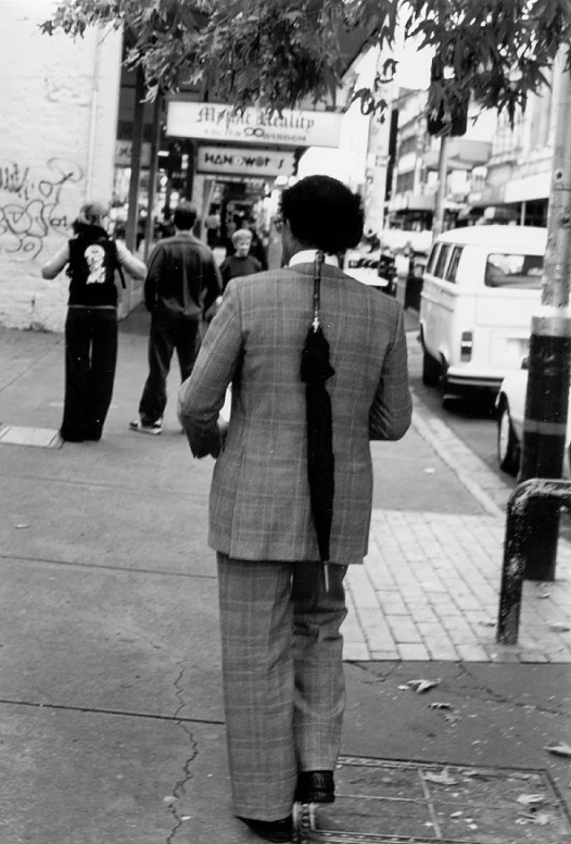 man in business suit on sidewalk holding umbrella over head