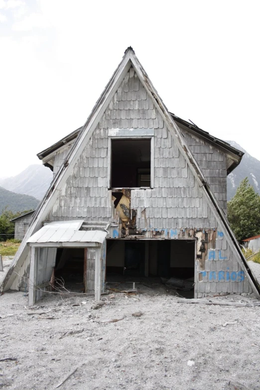 an old grey house in the shape of a triangular building