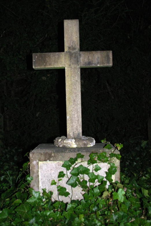 an old stone cross in the dark by itself