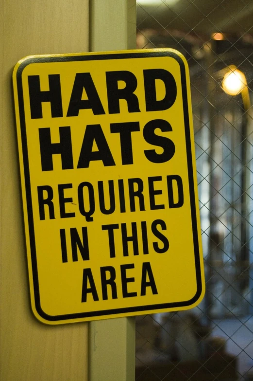 a sign posted on the door to a restaurant that says hard hats required in this area