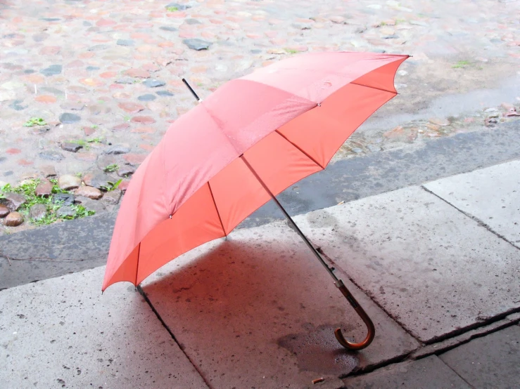 an open red umbrella sitting on top of a sidewalk