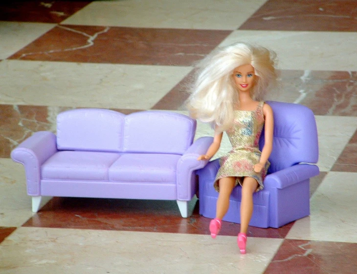a doll is sitting on a couch in front of a tiled floor