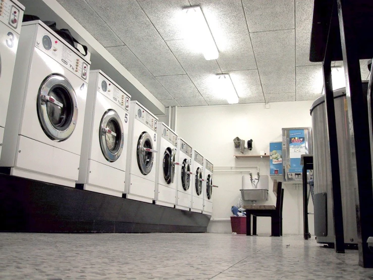 laundry machines sitting on tiled floors inside of a washer and dryer facility