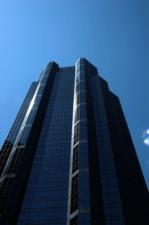 an extremely tall building with some clouds in the sky