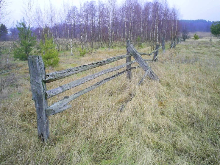 a weathered wood fence on a grassy field