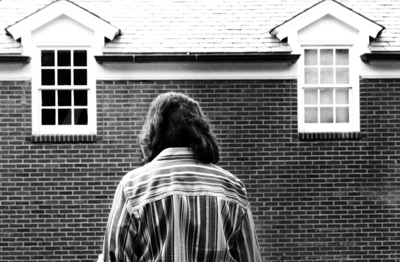 woman in striped shirt walking in front of brick building