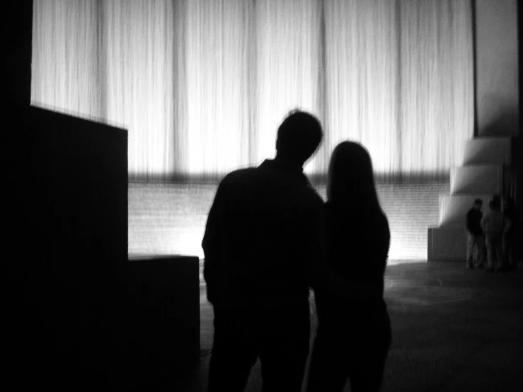 a man and woman stand in front of curtained windows