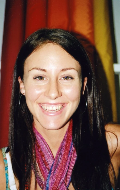 a woman is smiling while posing with her scarf around her neck