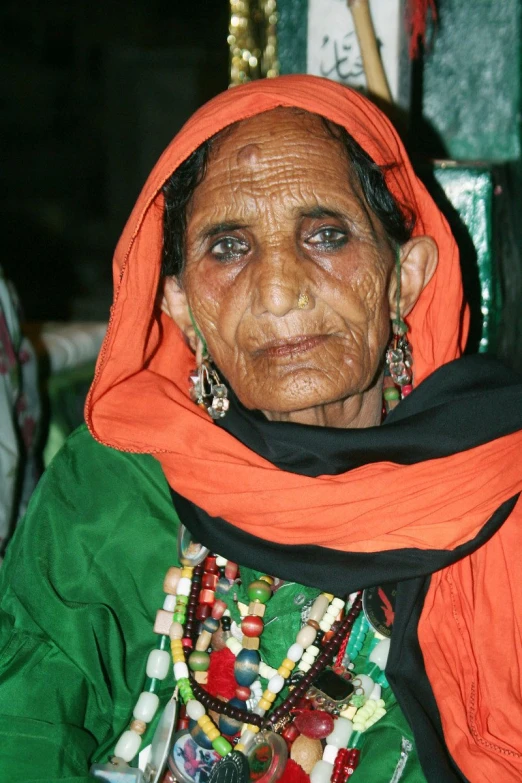the elderly woman is wearing bright clothing and a colorful scarf
