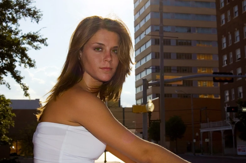 a young woman in a white top posing in front of a skyscr